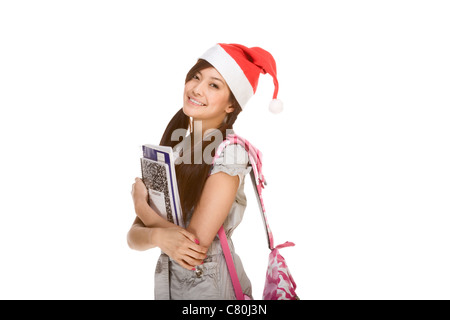 Asian schoolgirl wearing red Santa Claus hat with backpack holding Composition book, notebooks Stock Photo