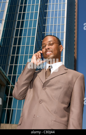 Businessman on the phone outdoors on background of reflective office building Stock Photo