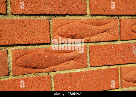 Fishes imprinted in building bricks in wall. Stock Photo