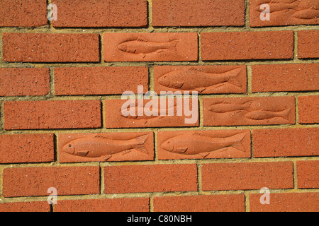 Fishes imprinted in building bricks in wall. Stock Photo