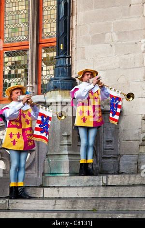 Trumpeters in ceremonial dress playing brass Aida fanfare trumpets before the Provincial Court, Grote Markt, Bruges, Belgium Stock Photo