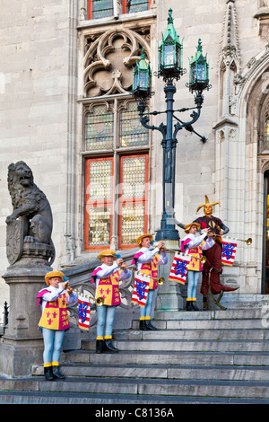 Jester &Trumpeters in ceremonial dress playing brass Aida fanfare trumpet before the Provincial Court Grote Markt Bruges Belgium Stock Photo