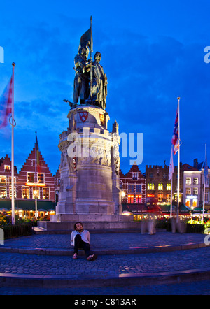 Tourist enjoying the night in front of the statue in the Grote Markt, Market Square, Bruges, Belgium at dusk, twilight. Stock Photo