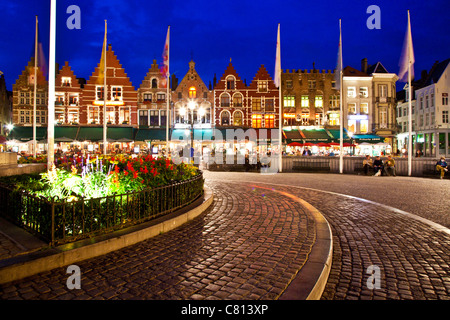 Bars, cafes, restaurants, and tourists in the Grote Markt or Market Square in Bruges, (Brugge), Belgium at twilight. Stock Photo