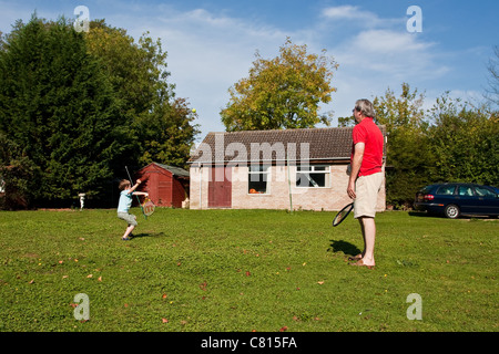 A middle aged man and his grandson playing tennis in the unusually warm weather in UK in October 2011 Stock Photo