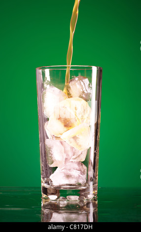 pouring soda in glass over green background