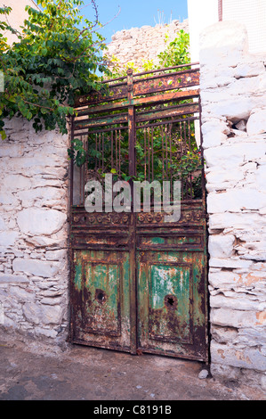 Old rusty door with peeling paint  leading to an abandoned courtyard on the Greek Cyclade island of Amorgos. Stock Photo