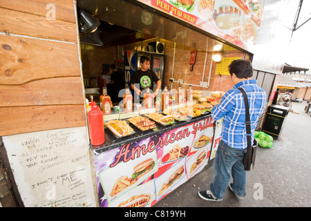 London Camden Town Lock Stables Village market customer at American Grill food stall hot dog hamburger wrap steak fish peri peri chicken Stock Photo