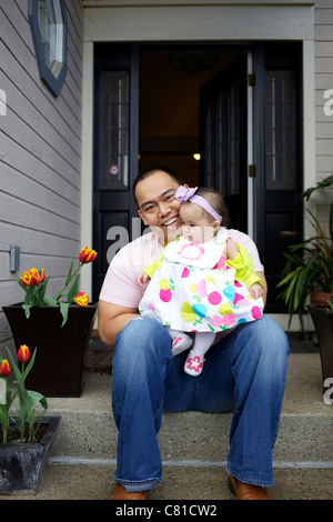 Father sitting on front stoop with baby girl Stock Photo