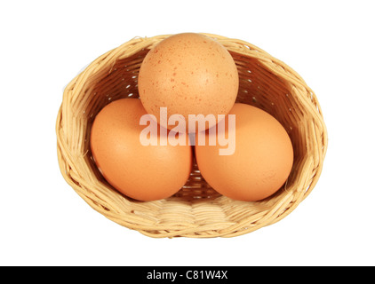 three brown eggs in a small wicker basket isolated on white Stock Photo