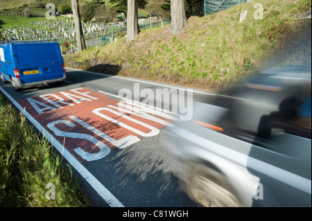 Traffic speeds over a Welsh language SLOW ARAF road sign on the A493 near Aberdyfi in the Snowdonia National Park, North Wales Stock Photo