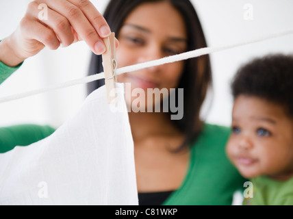 African American mother and son hanging clothing on clothes line Stock Photo