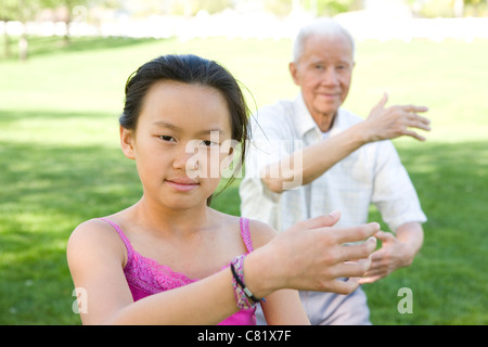 Senior Chinese grandfather and granddaughter doing tai chi outdoors Stock Photo