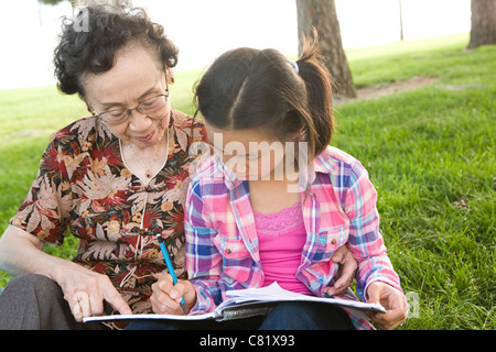 Chinese grandmother watching granddaughter doing homework Stock Photo