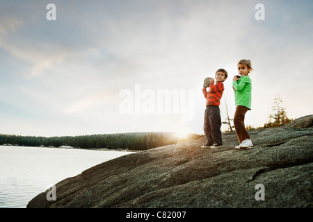 Children holding rocks near remote lake Stock Photo