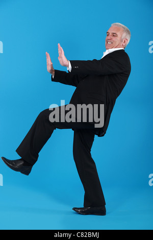 middle-aged man in suit pushing invisible furniture Stock Photo