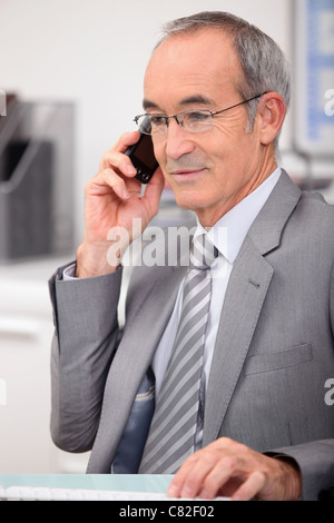 65 years old man wearing a grey suit and calling Stock Photo
