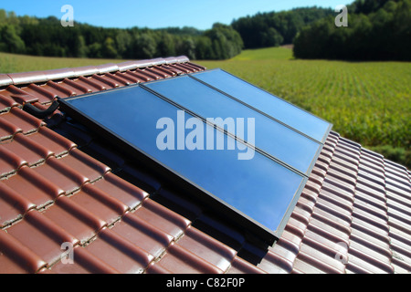 Solar energy. Water solar collector on a red metal roof Stock Photo - Alamy