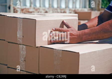 Close up of man's hands stacking boxes at an outdoor warehouse. Stock Photo