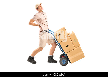 Full length portrait of a delivery boy, suffering from a back pain, pushing a hand truck Stock Photo