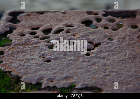 A rusty, damaged cap to a mooring post located on a beach Stock Photo