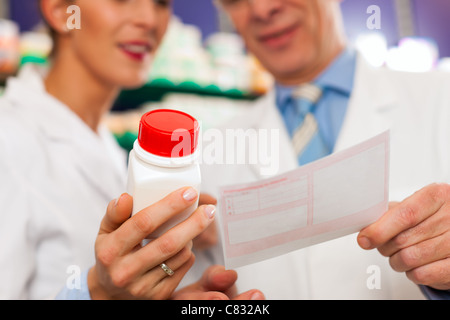 Two pharmacists with pharmaceuticals in hand consulting each other in a pharmacy Stock Photo