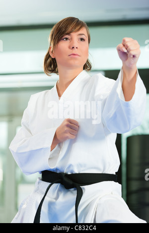 Woman in martial art training in a gym, she is wearing a black belt Stock Photo