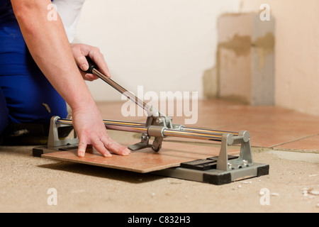 Construction worker is cutting tiles at home Stock Photo