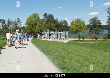 Tourists on a pathway with Horse carriages on the Herreninsel, Chiemgau Upper Bavaria Germany Stock Photo