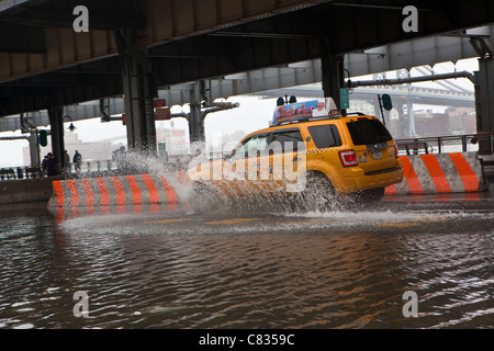Flooded street under Manhattan Bridge in NYC, during Hurricane Irene. Taxi passing by. New York. USA Stock Photo