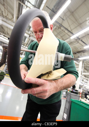 An employee works on a Bentley motor car steering wheel at the company's factory in Crewe, U.K. Stock Photo