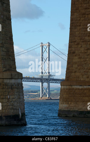 The Forth Road Bridge spanning the Forth Estuary in Scotland seen between the stone supports of the Forth Rail Bridge Stock Photo