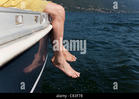 Woman dangling feet from sailboat Stock Photo
