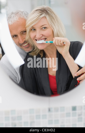 Woman brushing her teeth with husband Stock Photo