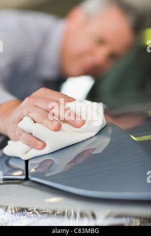 Salesman shining car in showroom Stock Photo