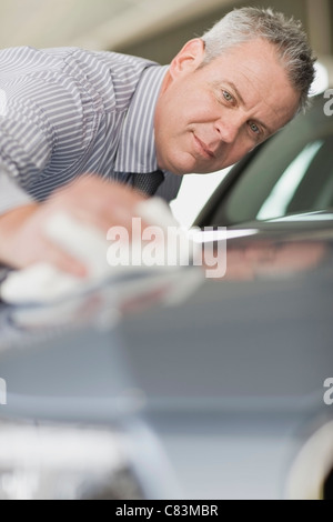 Salesman shining car in showroom Stock Photo