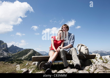 Couple sitting on bench on hilltop Stock Photo
