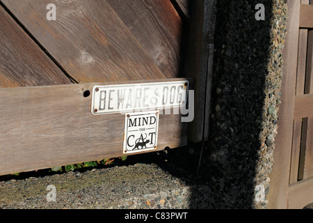 Beware of dog and mind the cat sign on a wooden fence Stock Photo