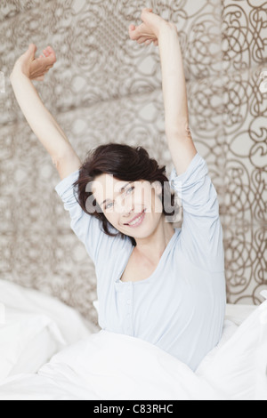 Smiling woman stretching in bed Stock Photo