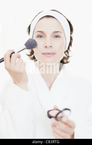 Woman in bathrobe applying makeup Stock Photo