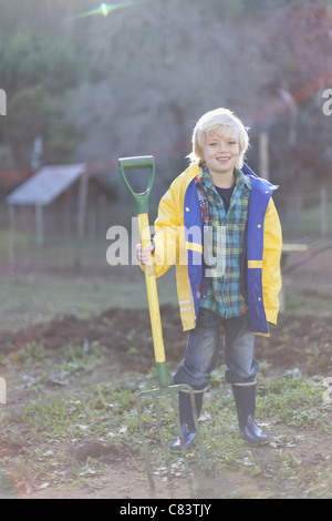 Boy holding pitchfork in garden Stock Photo