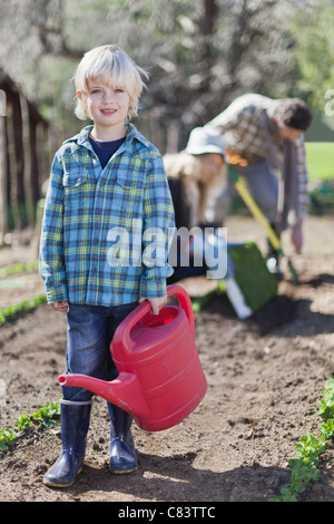Boy carrying watering can in garden Stock Photo