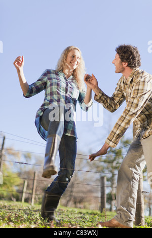 Couple climbing over wire fence outdoors Stock Photo