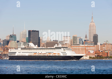 Holland America Line cruise ship M/S Veendam heads south on the Hudson River  past the mid-town skyline in New York City. Stock Photo