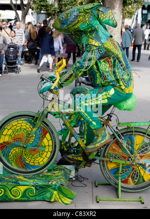 Entertainer dressed up as a chameleon on a bike on London's South Bank Stock Photo