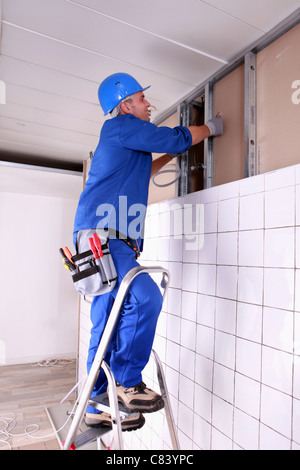 Construction worker panelling wall Stock Photo