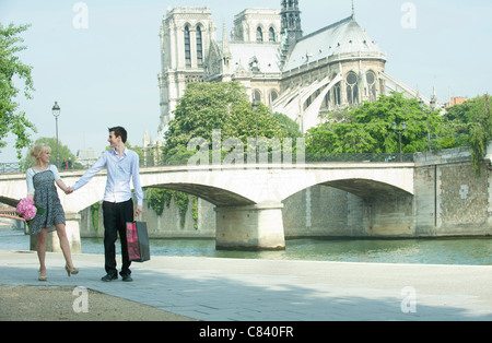 Caucasian couple walking along city river near Notre Dame Stock Photo