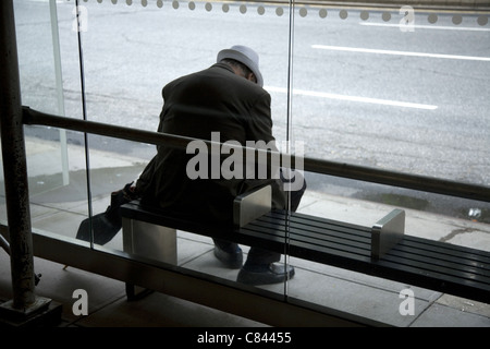 Older man waits alone for a bus on the Upper West Side of Manhattan. Stock Photo