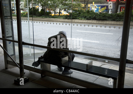 Older man waits alone for a bus on the Upper West Side of Manhattan. Stock Photo