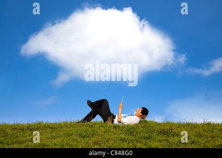 cloud background and happy businessman working with tablet pc on the green grass Stock Photo